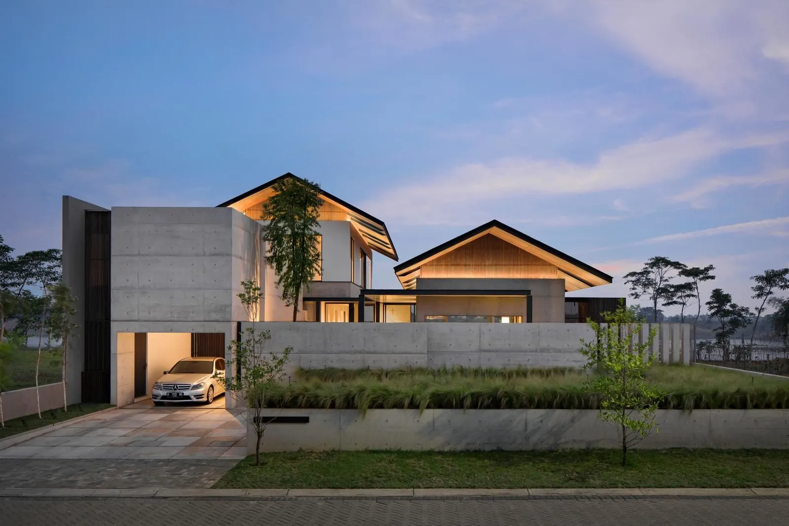 一棟現代住宅,擁有混凝土外牆與簡約設計,暖光照亮整體。