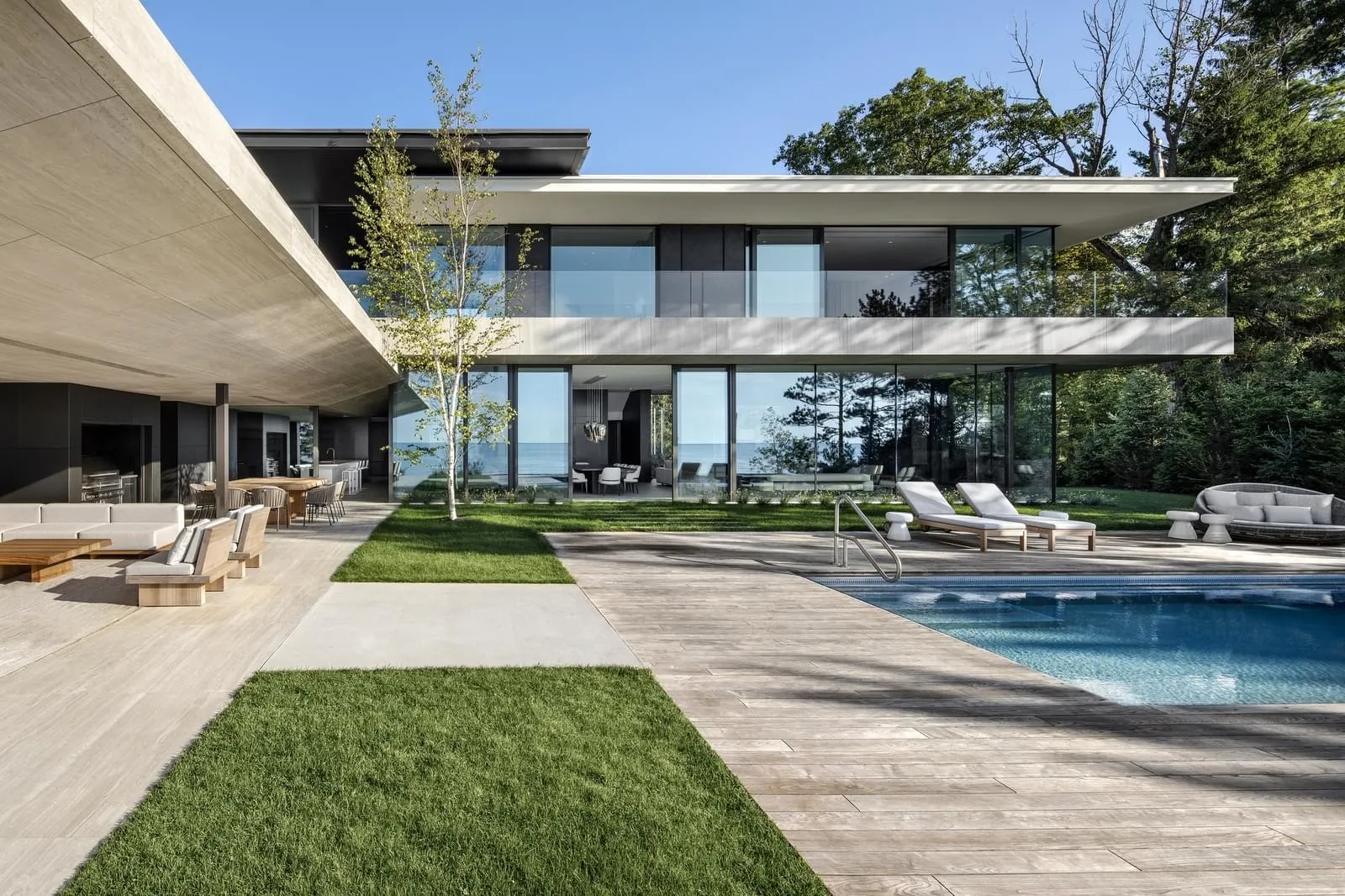 Modern residential exterior featuring a swimming pool and large glass walls.