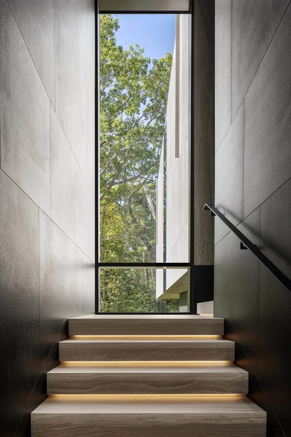 Modern staircase with light-up steps leading to a view of a forest.