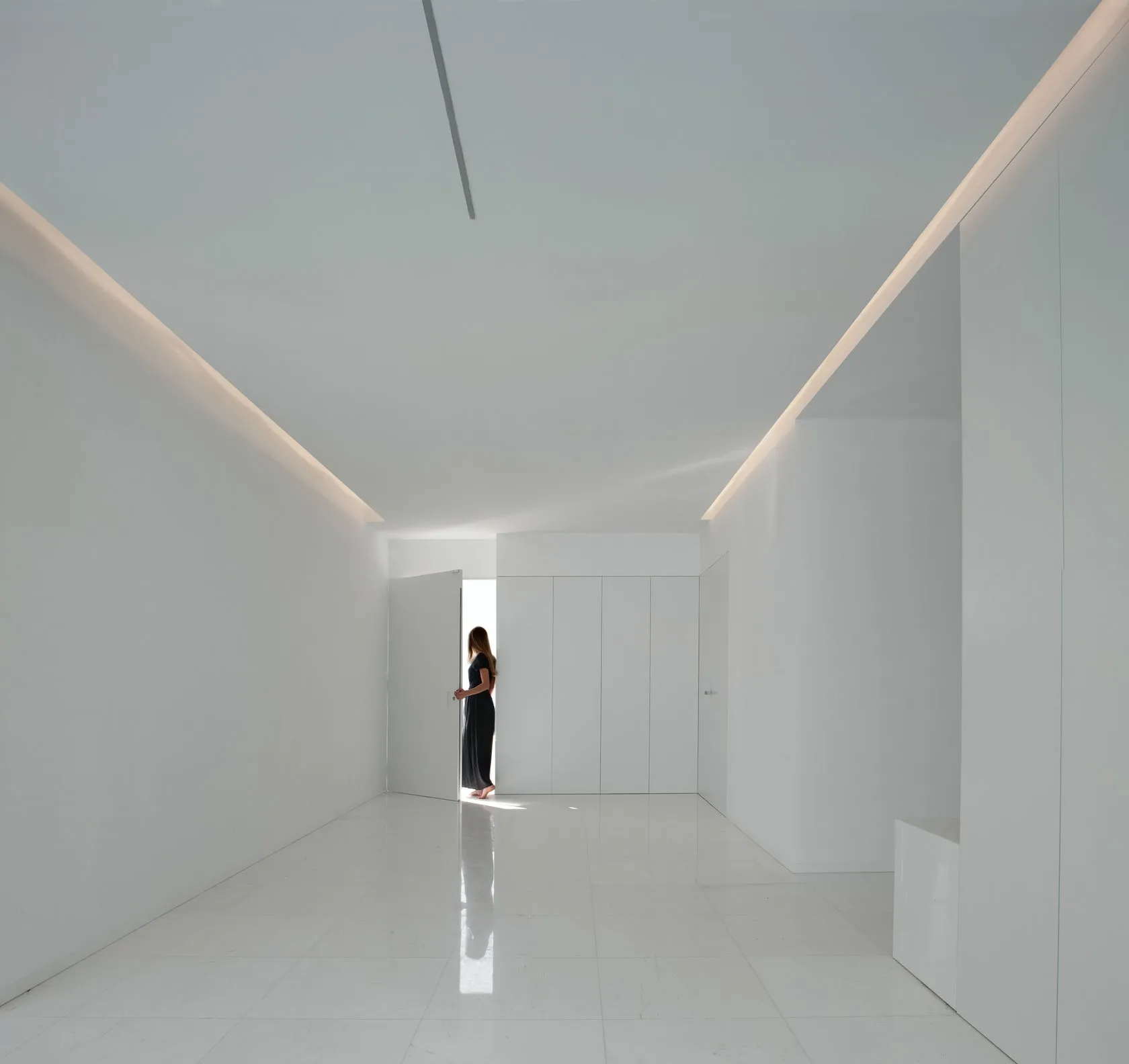 Minimalist interior space with white walls, floor, and lighting fixtures.