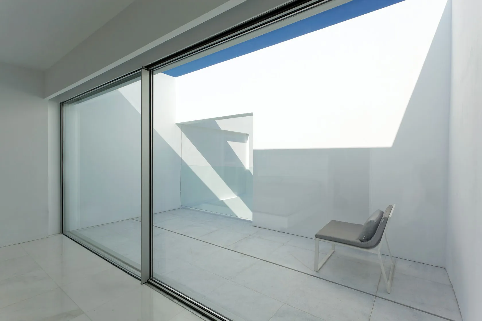 A minimalist balcony featuring glass walls, concrete floor, and metal accents.
