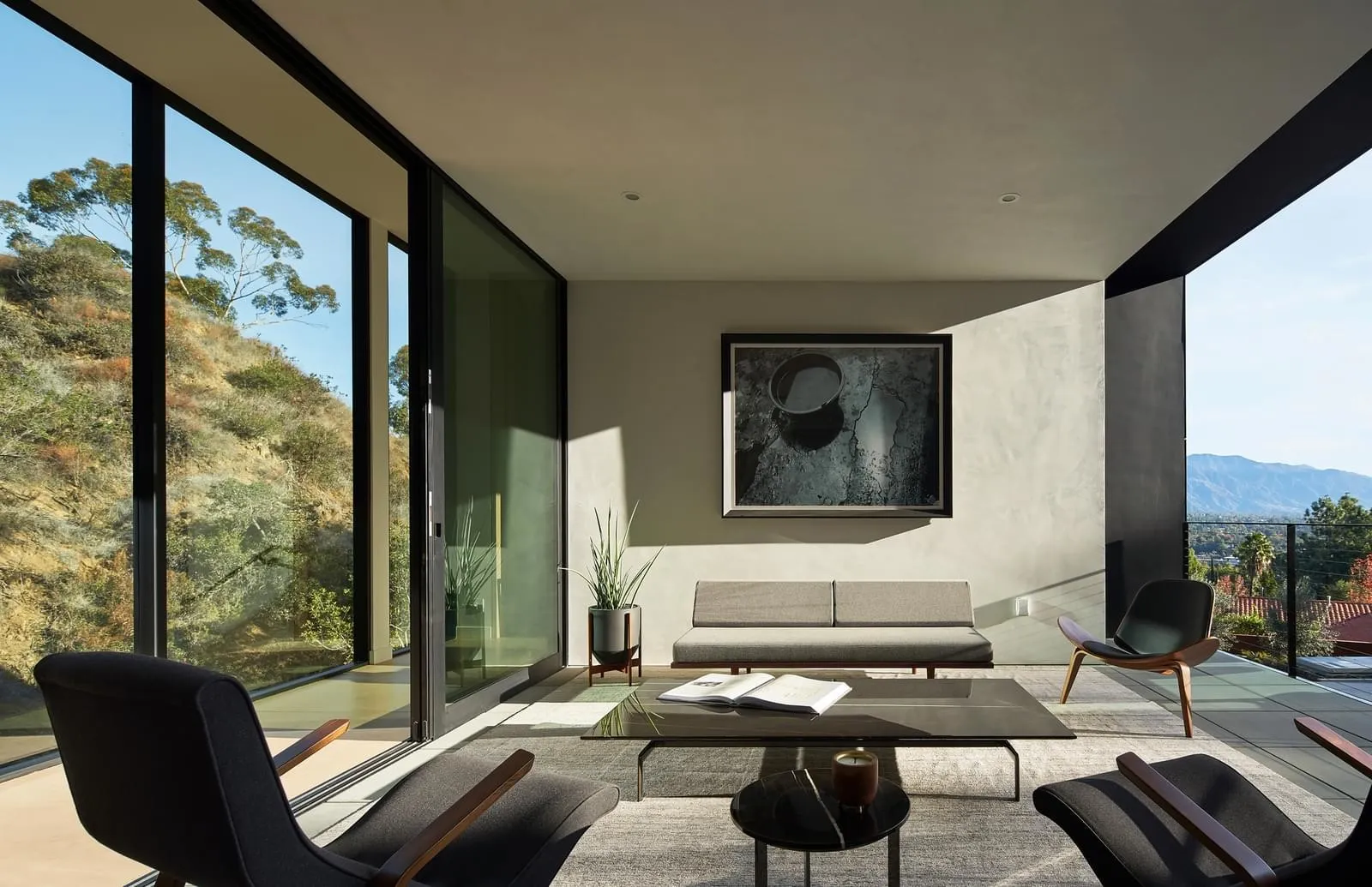 A minimalist living room with concrete walls and a glass window overlooking a scenic landscape.