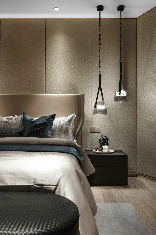 A modern bedroom with fabric bedding and glass pendant lights.