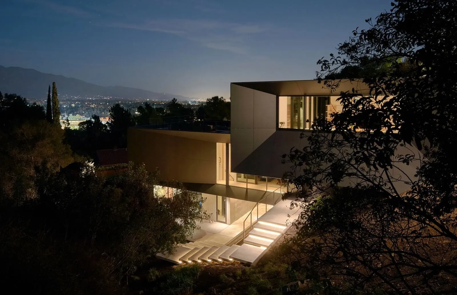 Modern residential house with concrete exterior illuminated at night.