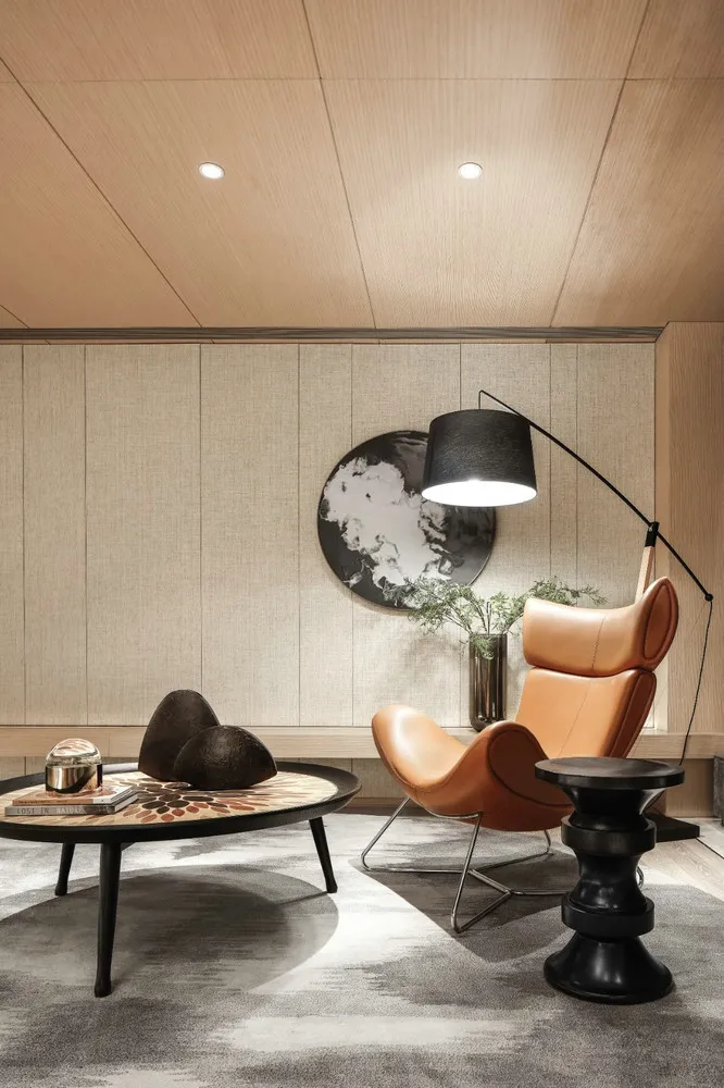 A modern living room with wooden walls, brown leather chairs, and a metal floor lamp.