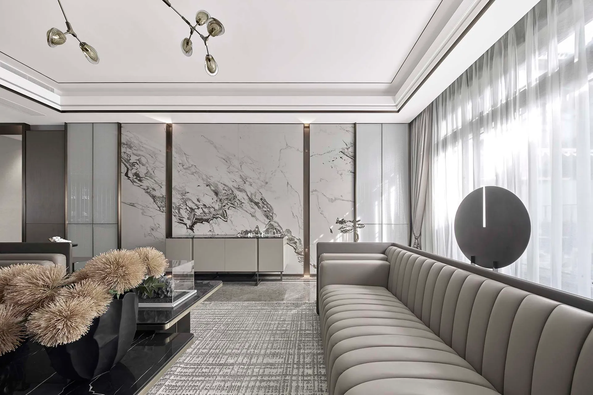 Modern living room with marble walls, glass furniture, and a contemporary chandelier.