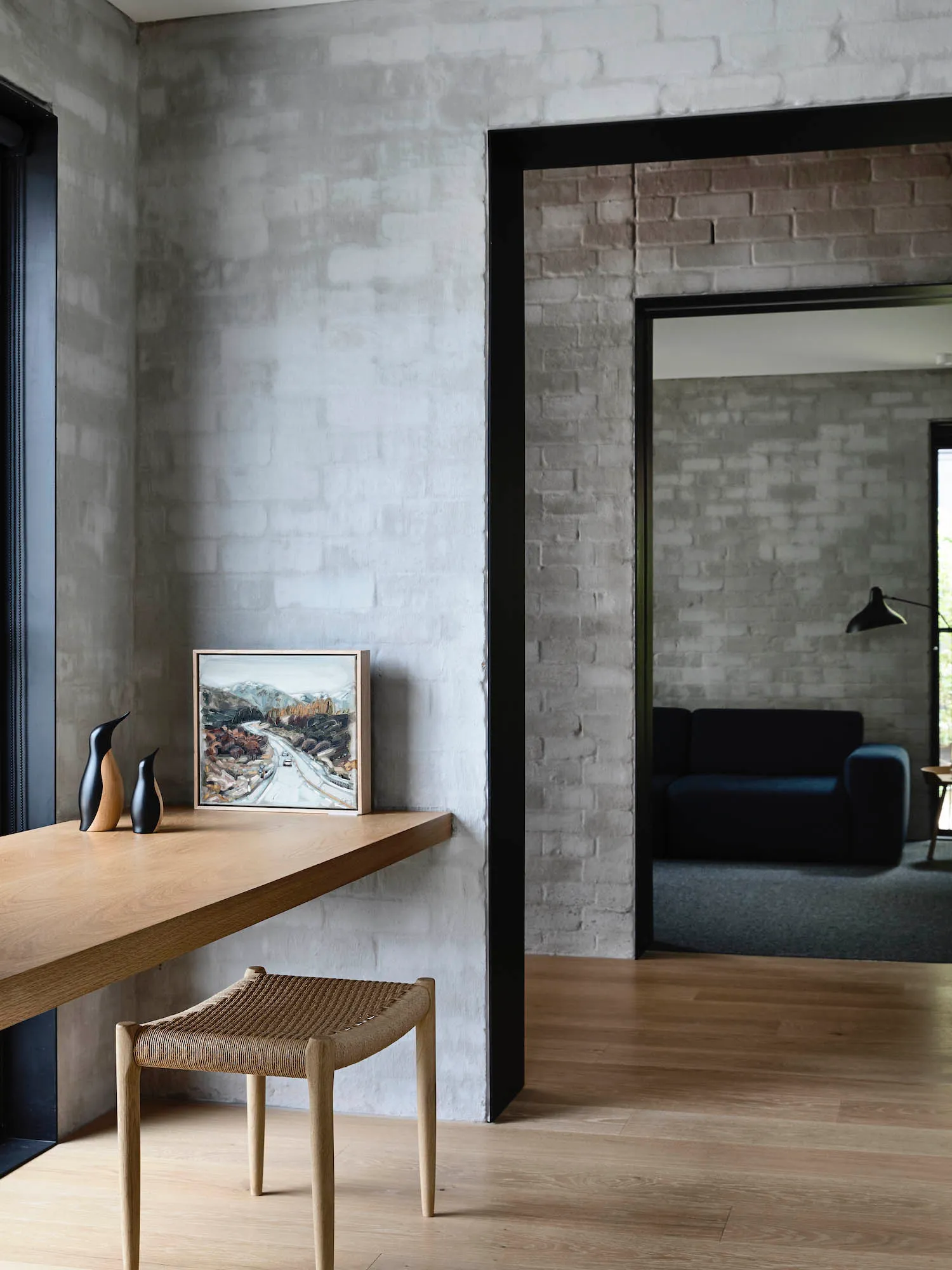A modern home office with a wooden desk, concrete walls, and brick accents.