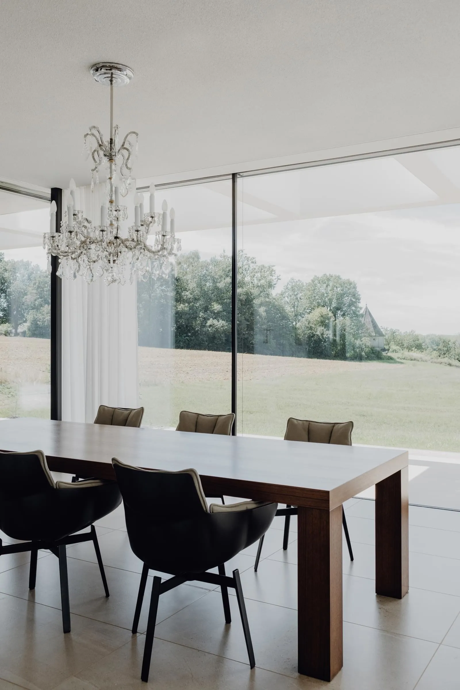 Modern minimalist dining room with a wooden table and black chairs.
