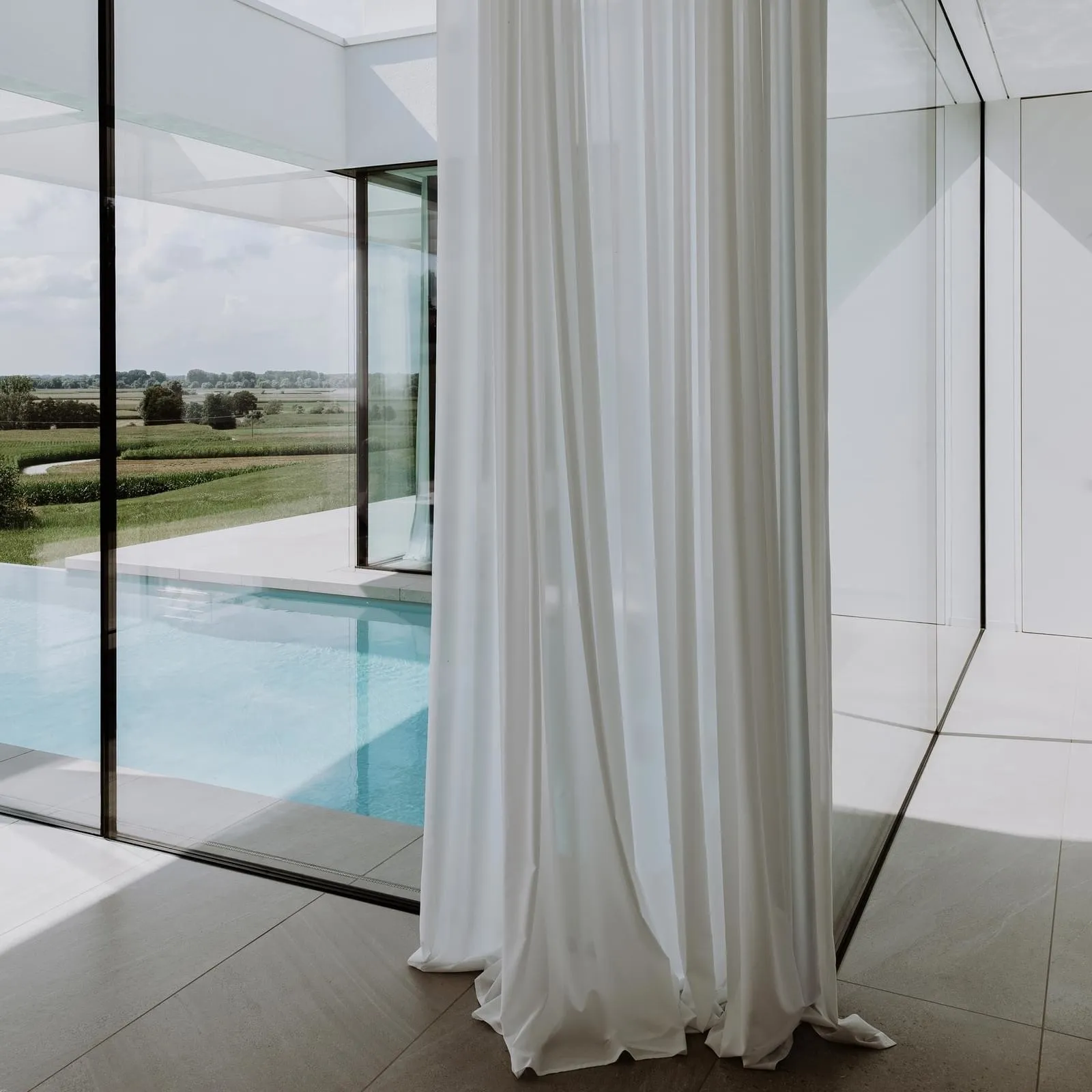 A modern living room featuring glass walls and a swimming pool.