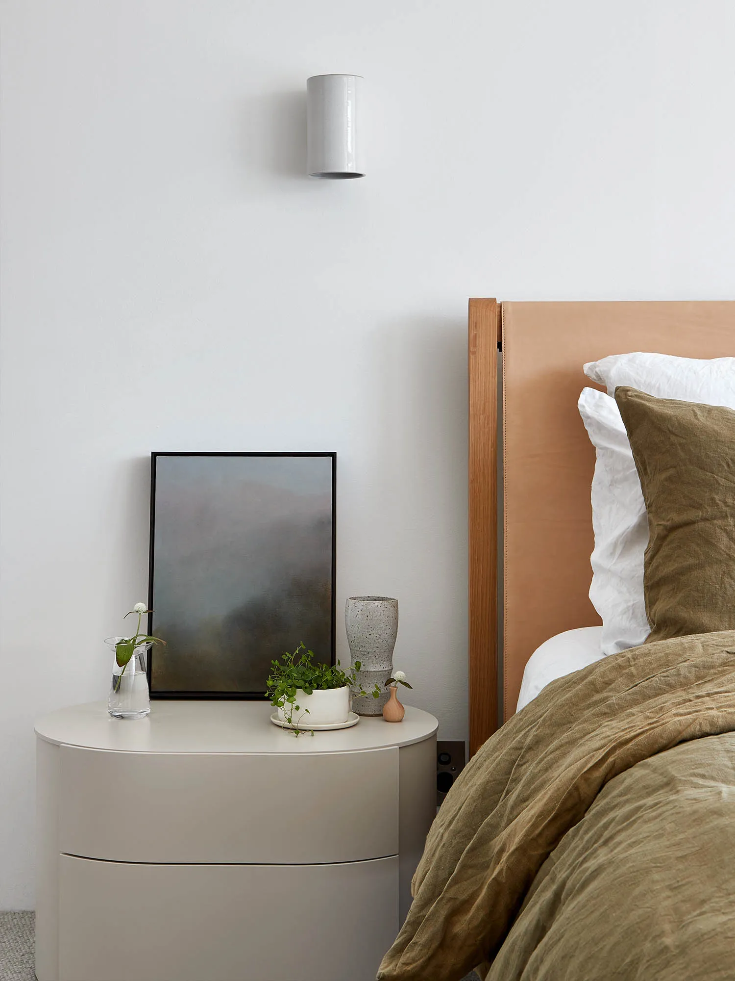 A minimalist bedroom featuring a wood headboard and neutral color scheme.