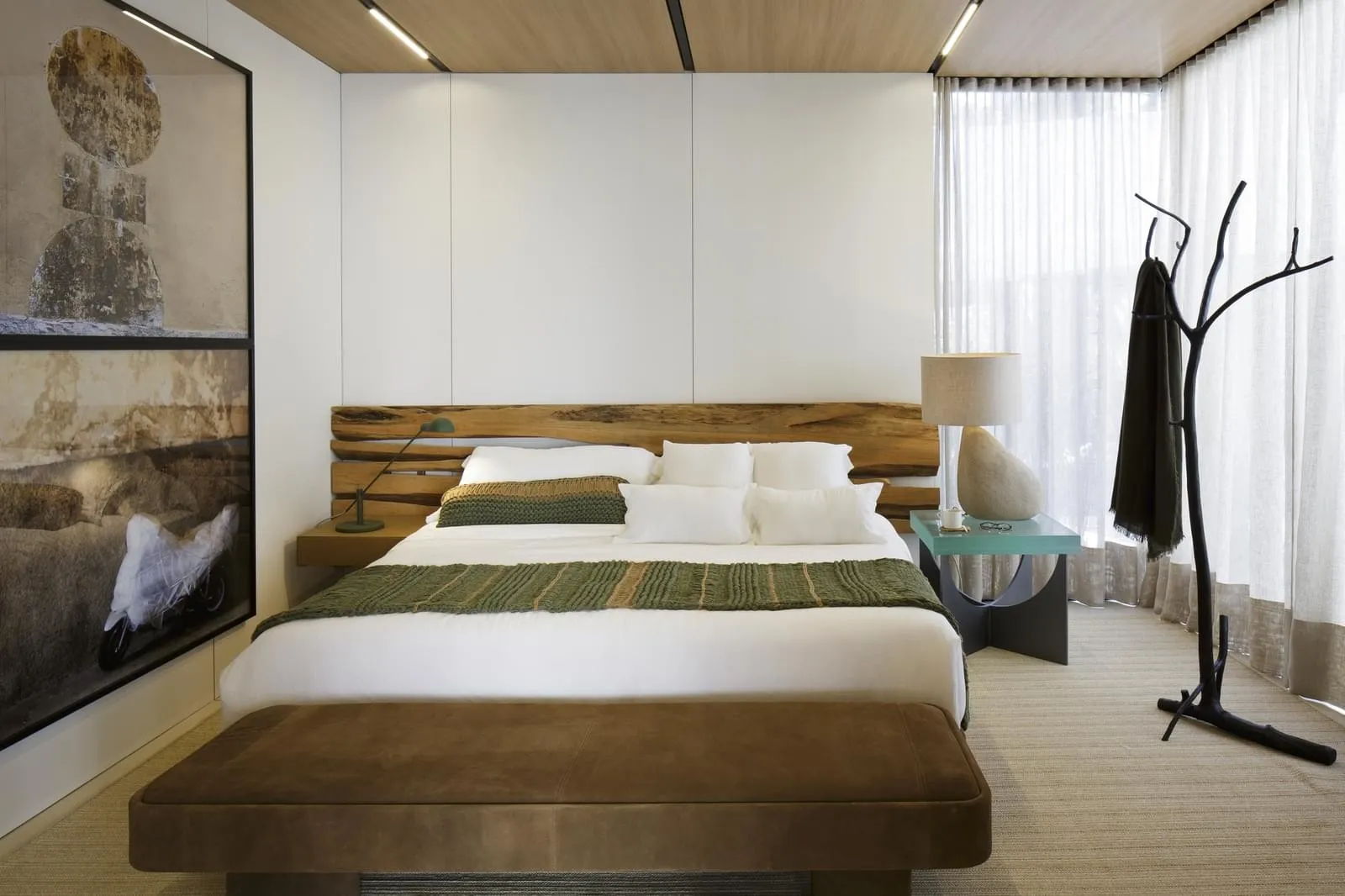 Modern bedroom featuring a minimalist design with a wooden platform bed, white bedding, and a green throw blanket.
