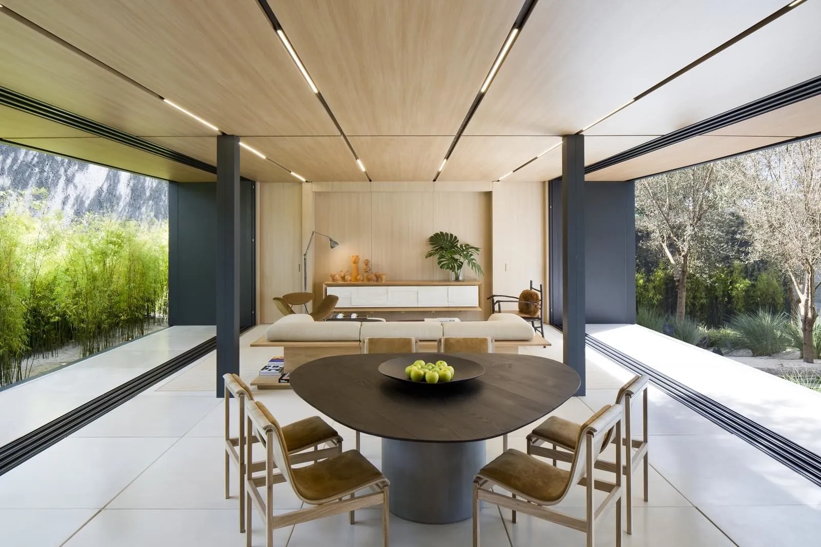 A modern minimalist living room with a wooden floor, white walls, and a large glass window.
