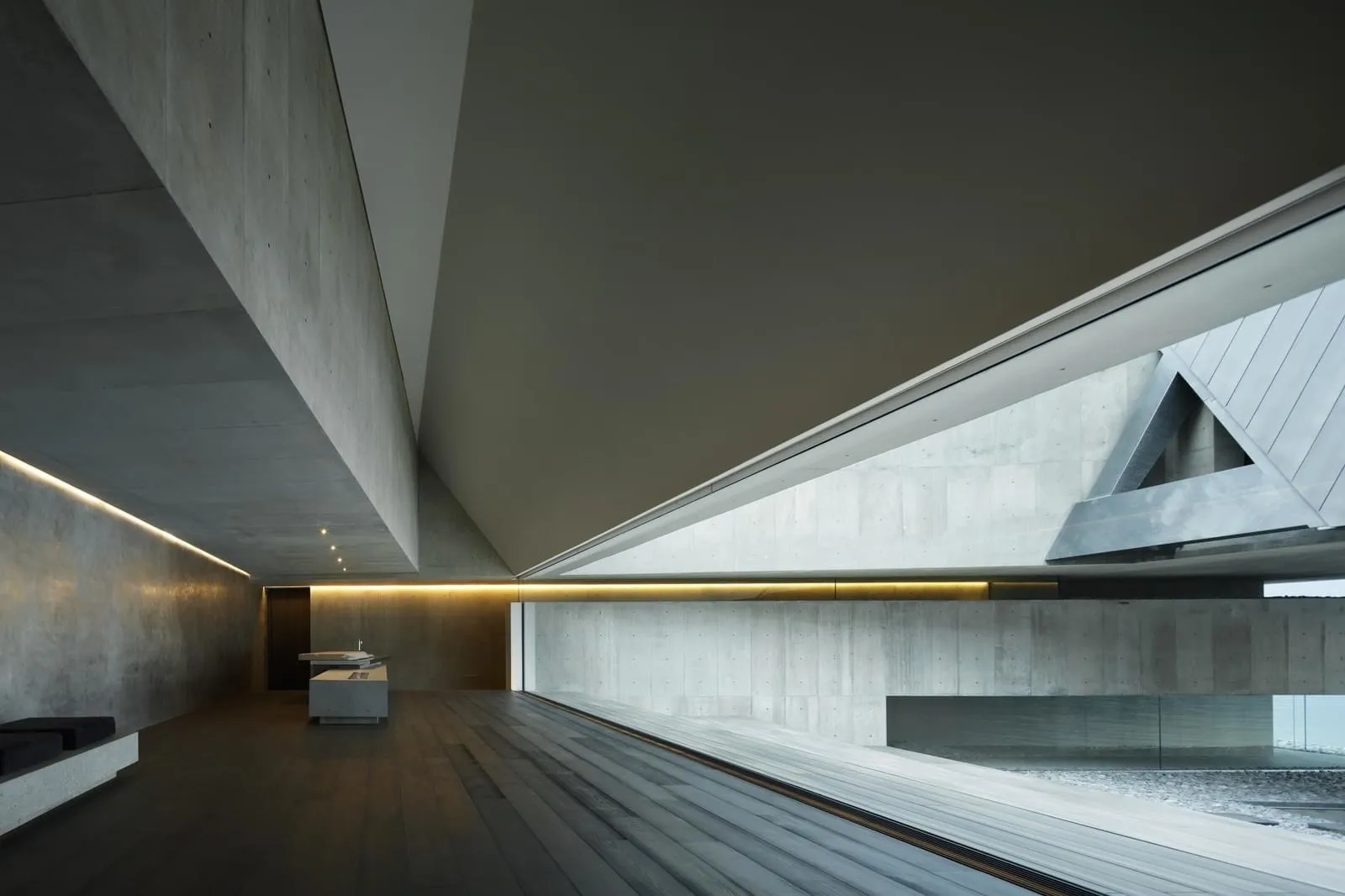 An industrial-style interior with exposed concrete walls and floor, featuring minimalist design and modern furnishings.