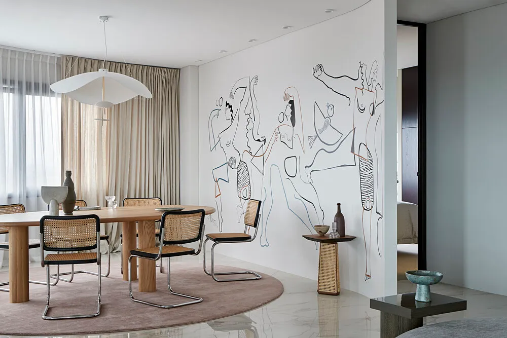 A modern dining room featuring a wooden table with cane chairs and metal accents.