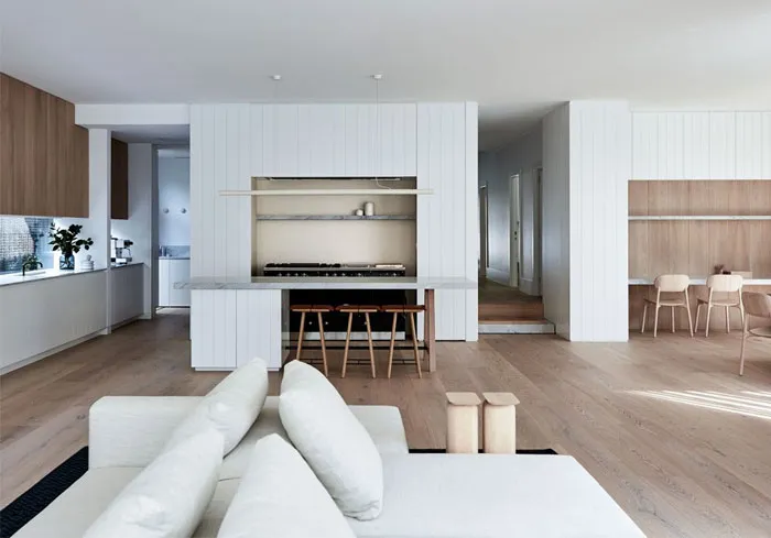 Modern living room and kitchen with open-concept design, featuring wood and marble materials
