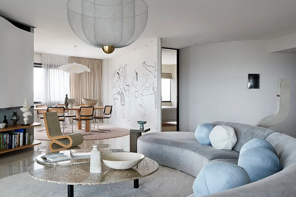 Modern living room featuring a sculptural sofa with round cushions, a round marble coffee table, and a large abstract mural o