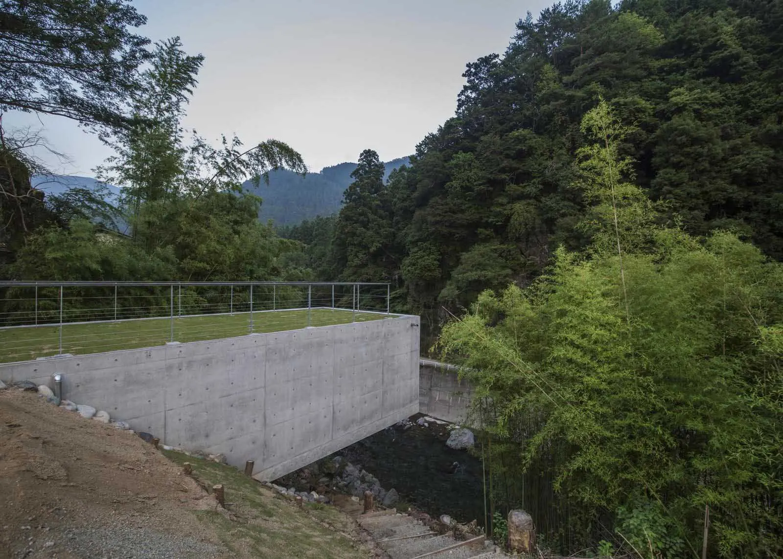 A modern outdoor architectural structure made of concrete and glass.