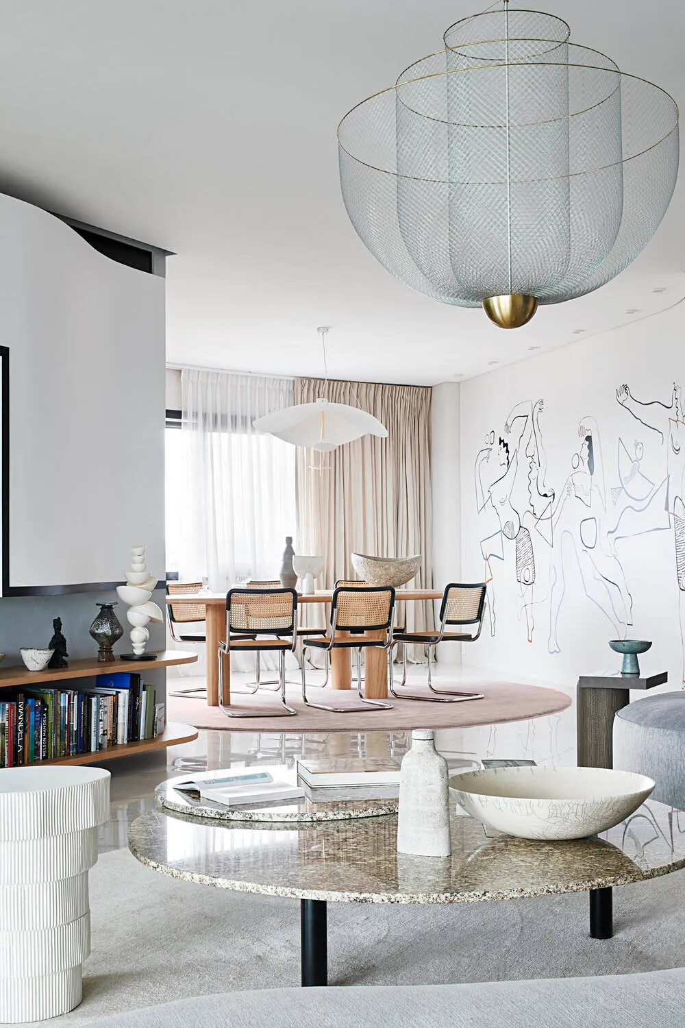 A modern living room featuring a granite coffee table, ceramic bowls, and metal lampshades.