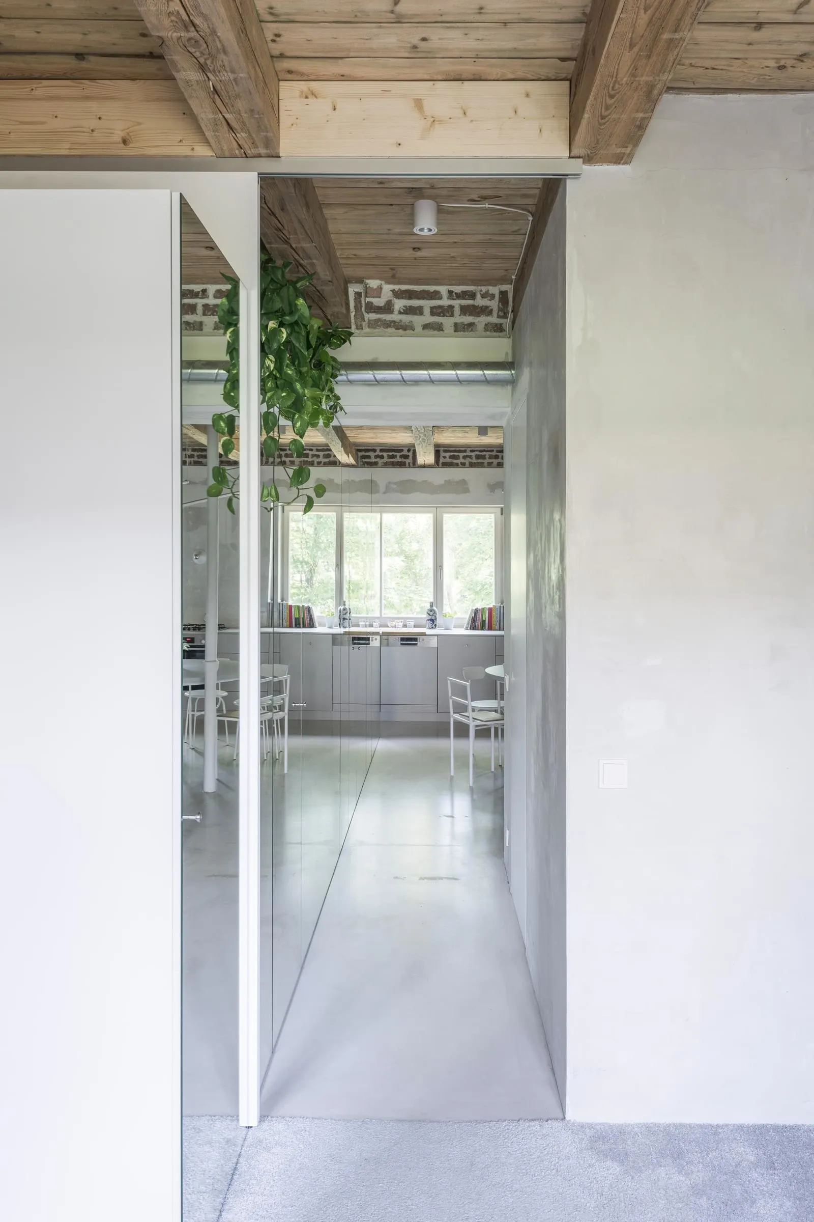 Modern minimalist kitchen with concrete flooring, white appliances, and exposed brick wall.