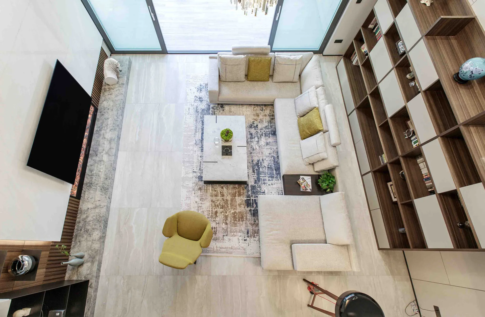 Minimalist living room with white walls, tile-blend carpets, and a large bookshelf.
