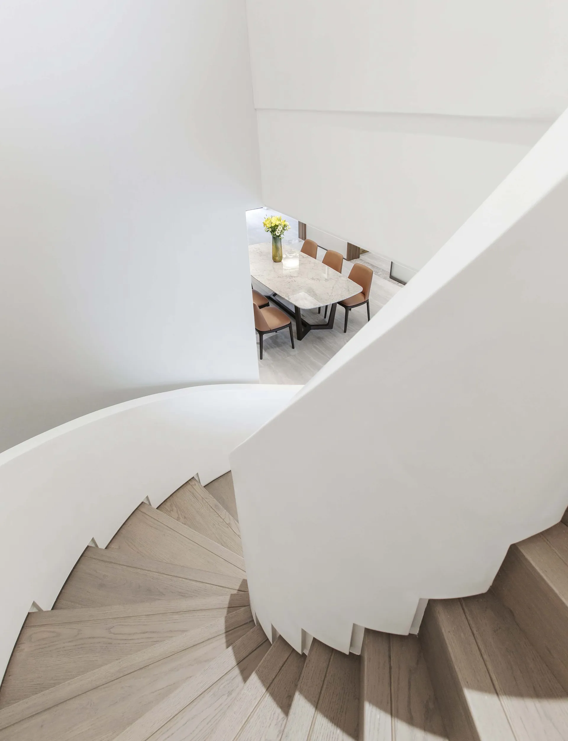 Modern staircase with white railings and wooden steps leading to a dining area.