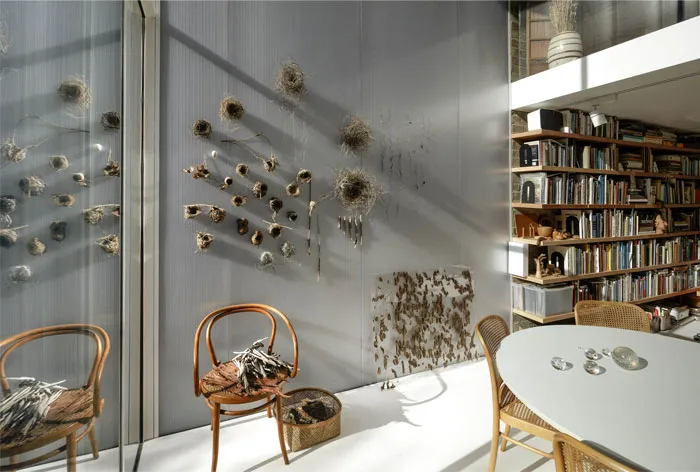 A minimalist living room and library featuring metal and glass elements.