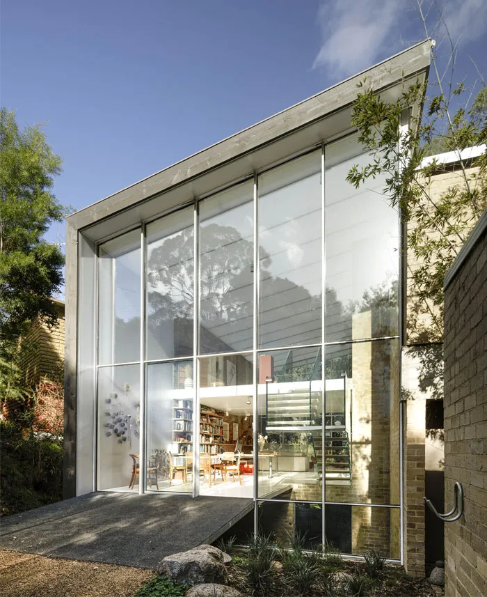 A modern house exterior featuring large glass panels creating a minimalist and sleek design.