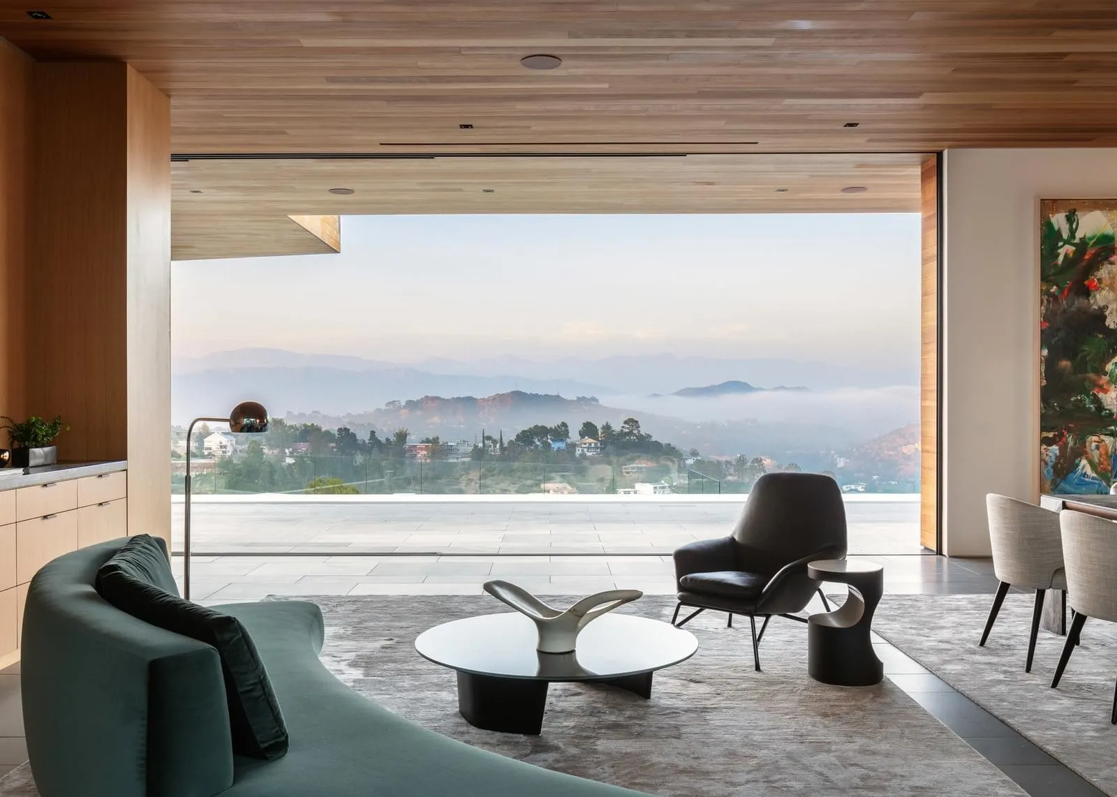Modern living room featuring minimalist furniture and a large window with a scenic mountain view.