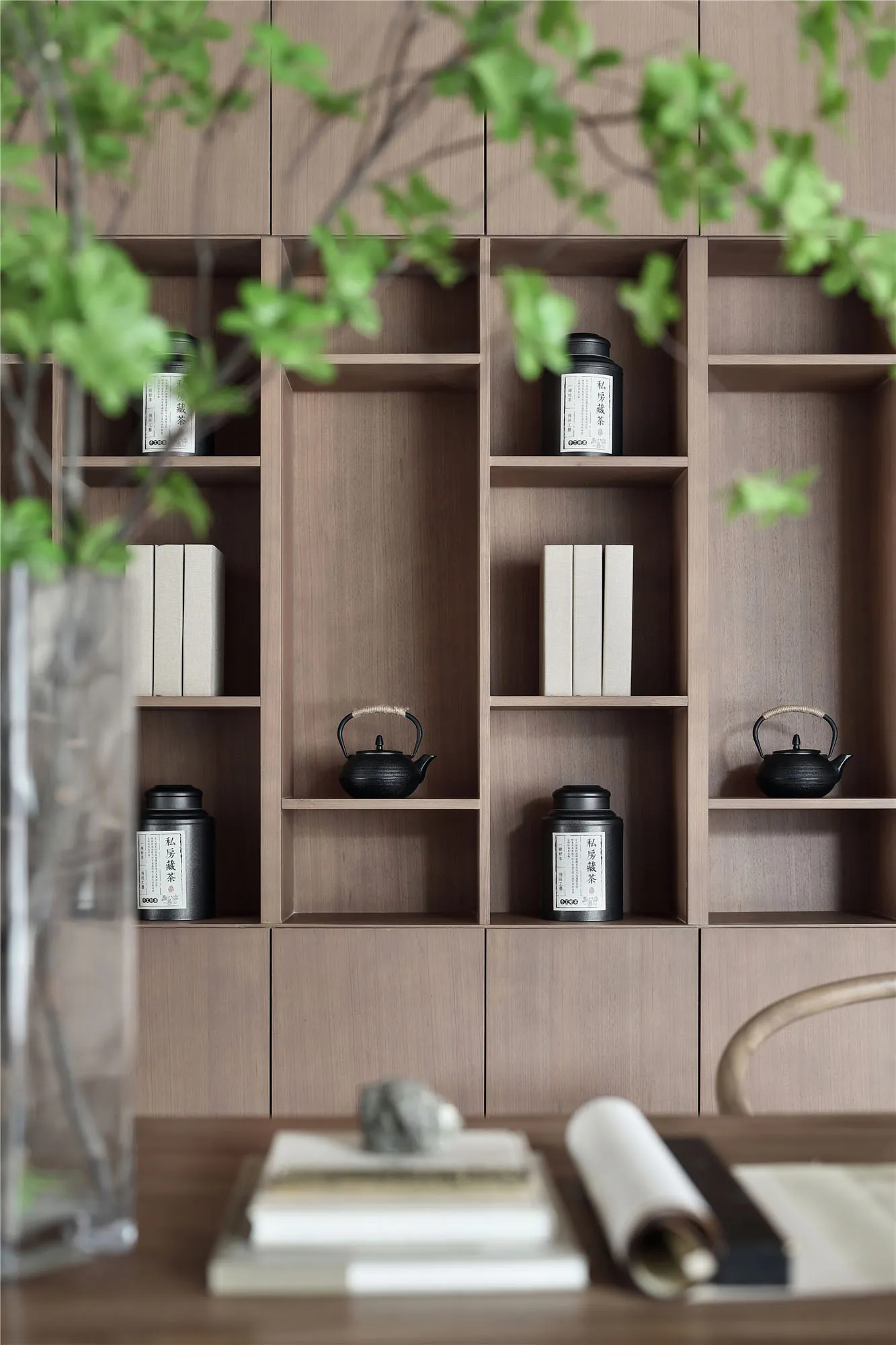 A neatly organized wooden bookshelf with books and tea canisters.