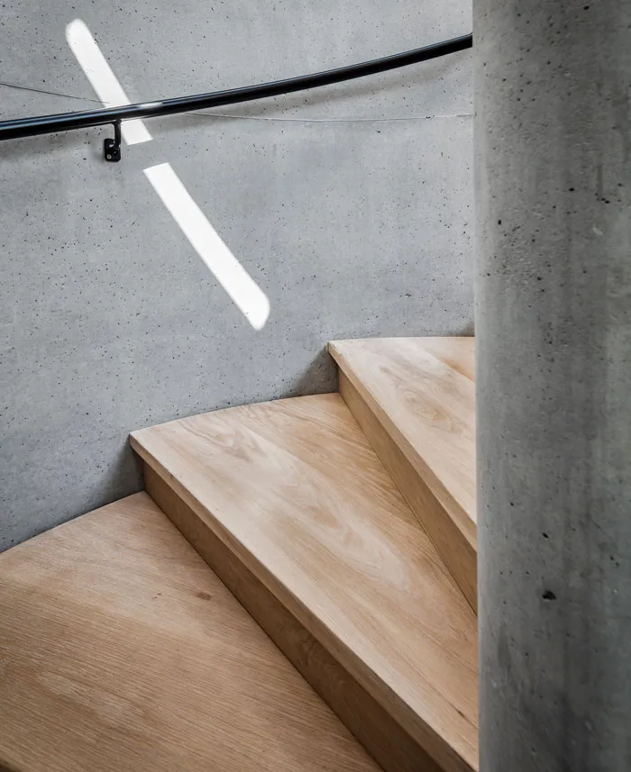 Modern industrial-style staircase with concrete walls and wood treads.
