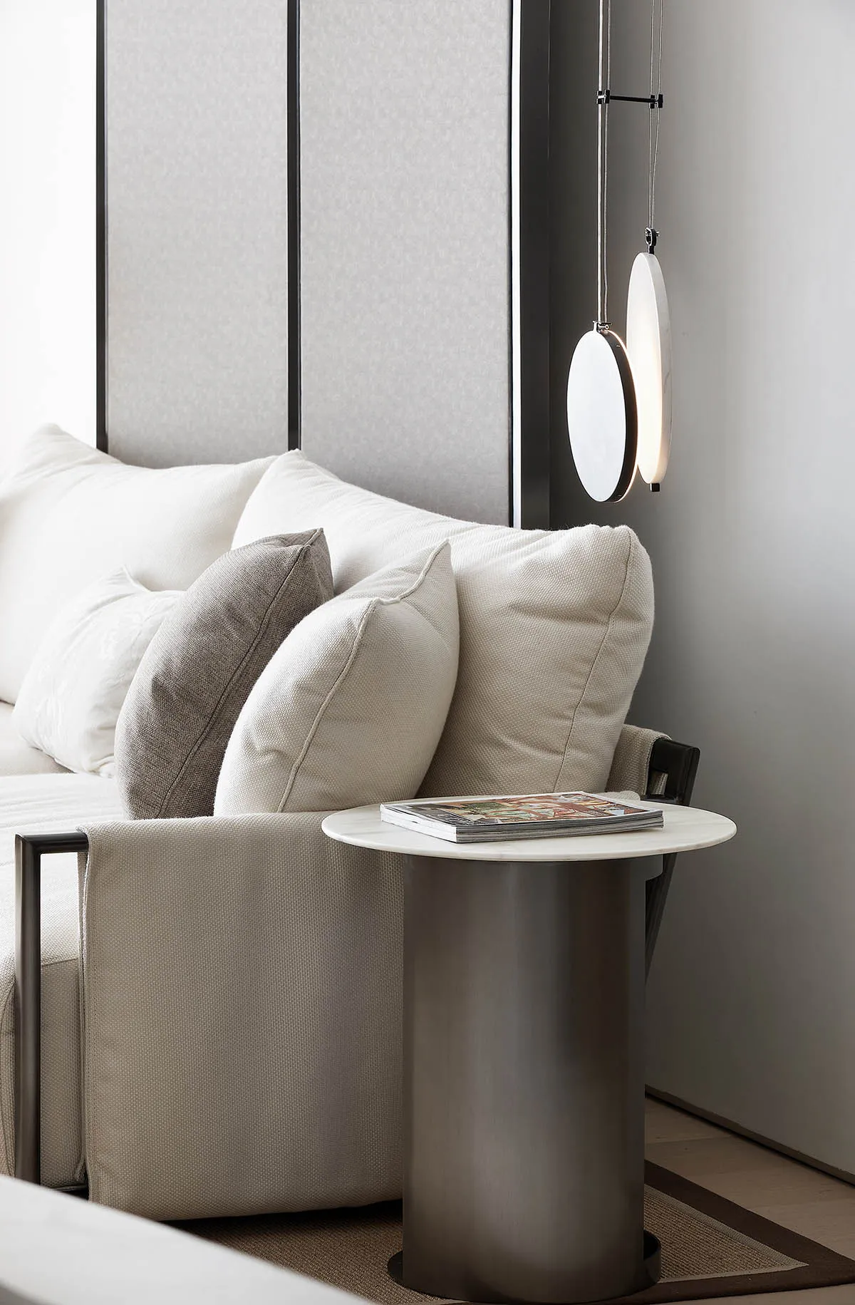 Modern, minimalist living room with a white sofa, pillows, and a side table.