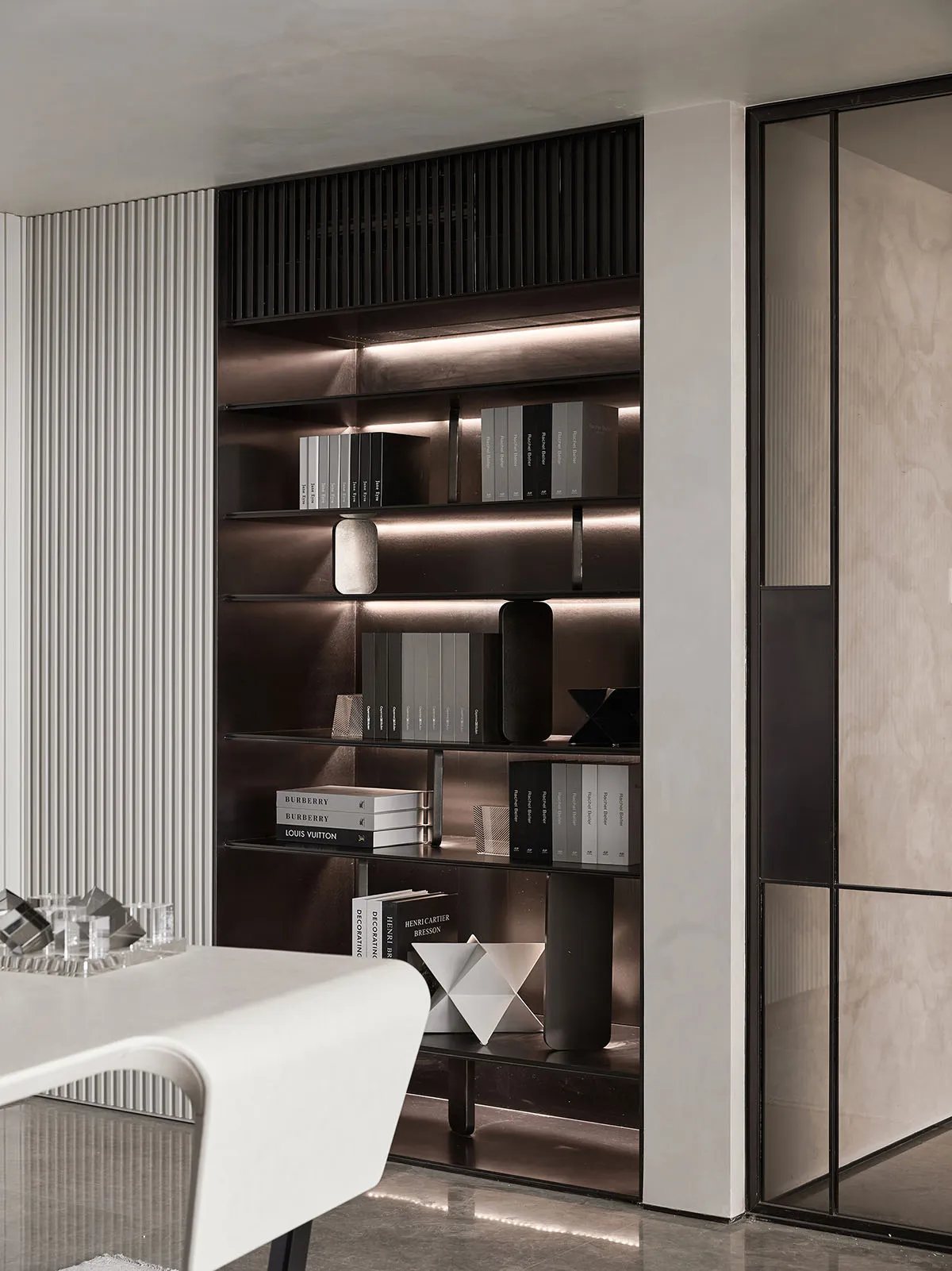 Modern minimalist bookshelf with glass and metal accents in contemporary interior design setting.