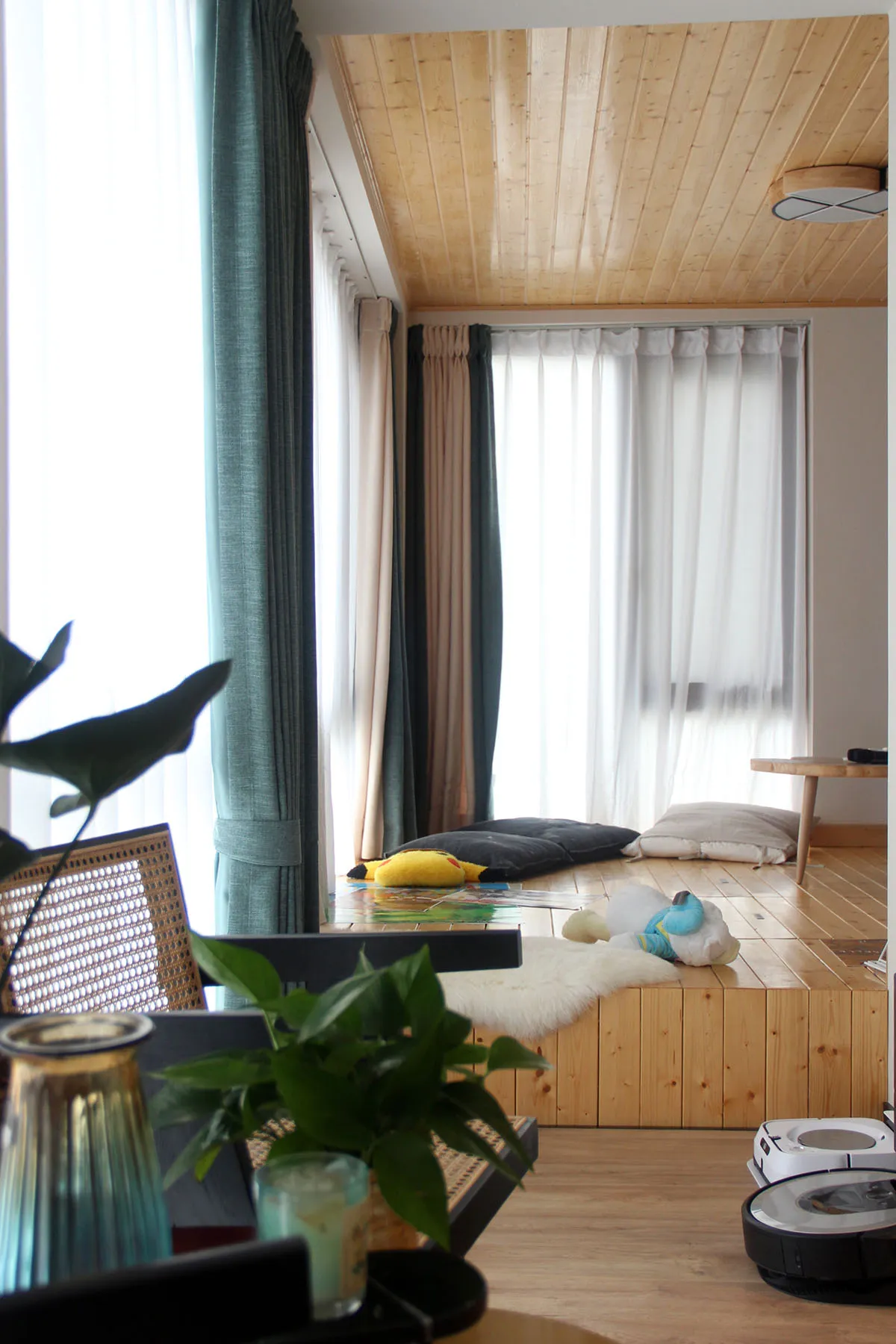 A modern living room with wood flooring, pillows, and curtains, showcasing a cozy and contemporary design.