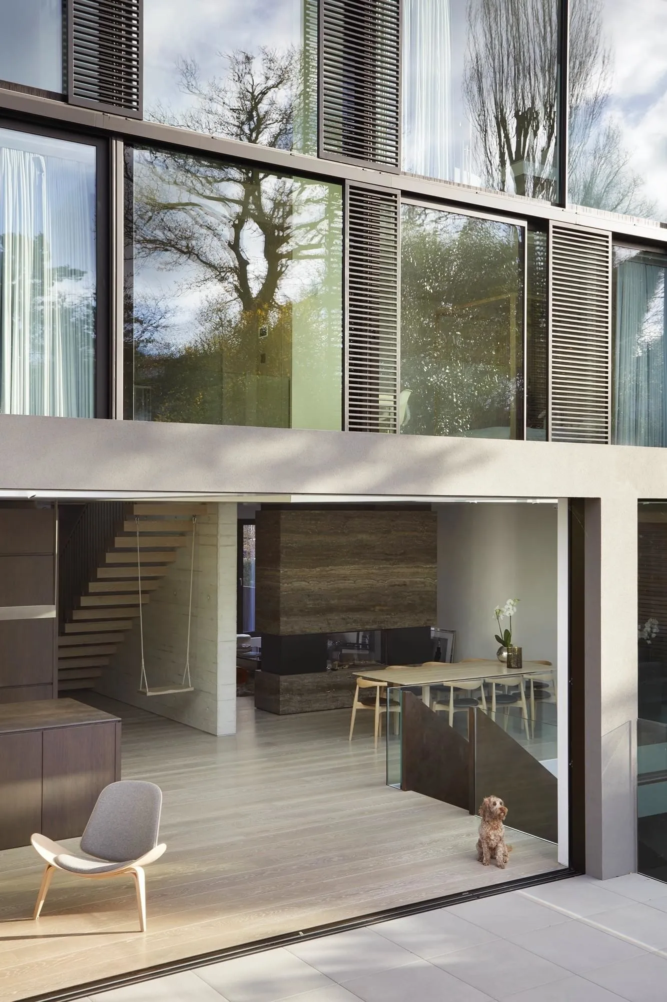 Modern residential space featuring wooden floors, concrete fireplace, and glass walls.