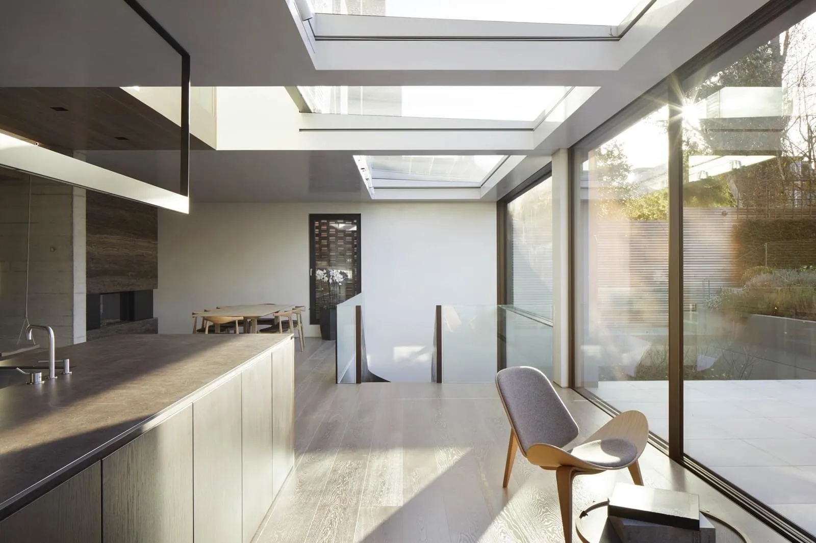 Modern residential interior featuring sleek glass and concrete materials, open-concept space with skylights and large windows