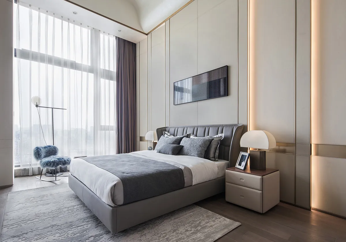 A modern bedroom featuring a textured fabric bed, minimalistic decor, and soft lighting.