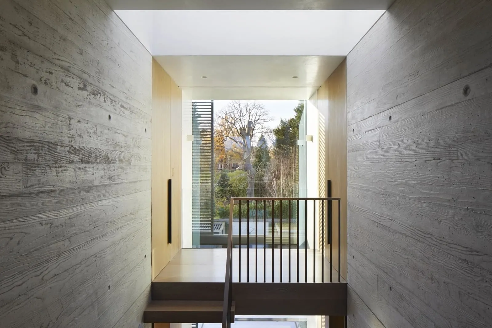 Concrete walls, wooden stairs, and glass wall in a modern interior design.