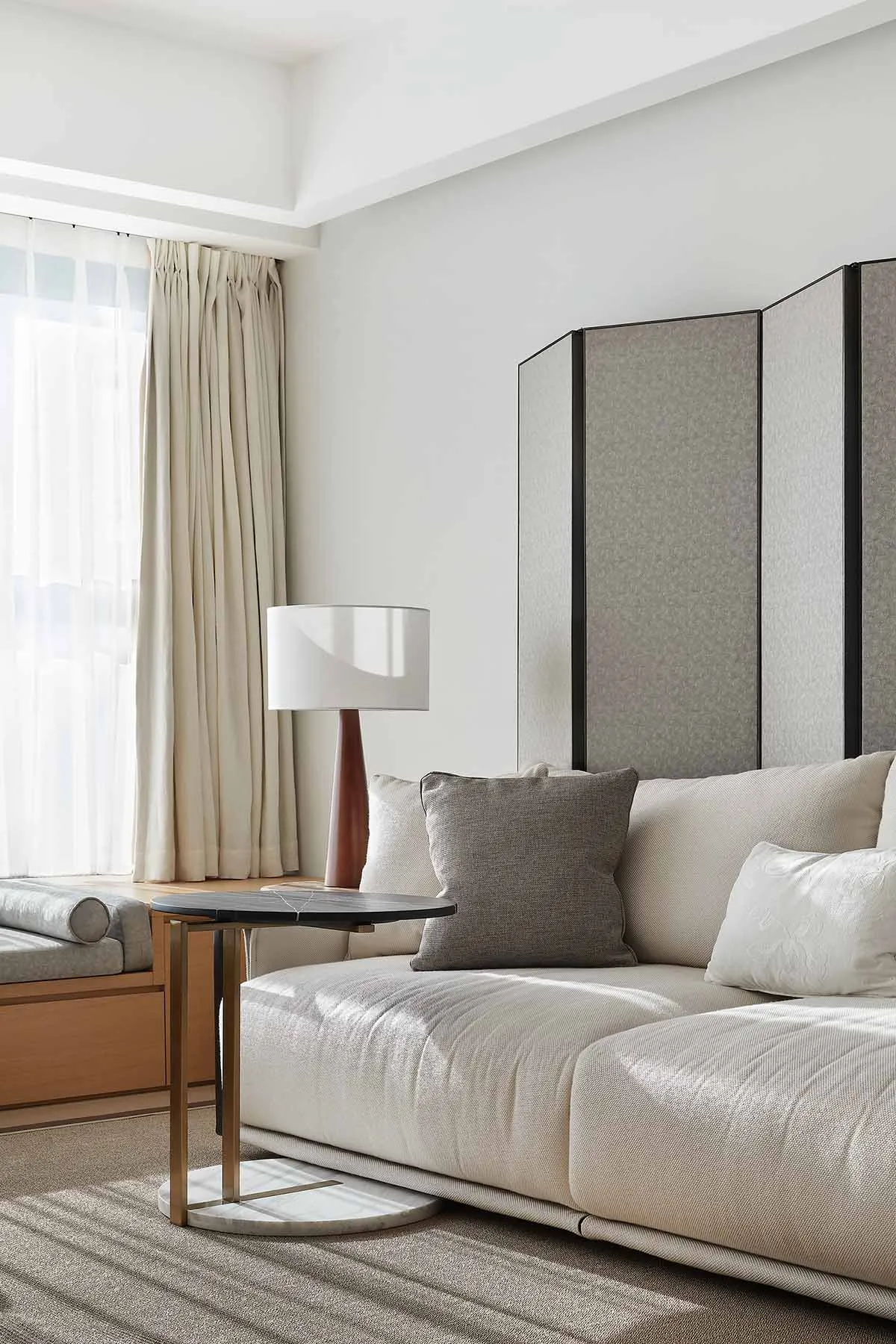 Modern living room featuring fabric sofa, wood coffee table, and glass divider