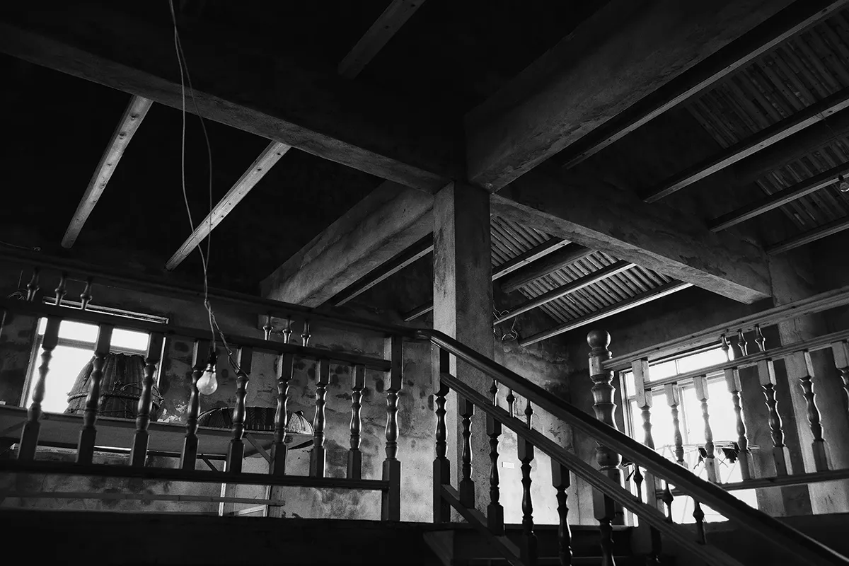 工業風建築內的混凝土樓梯,搭配木質扶手與挑高天花板。