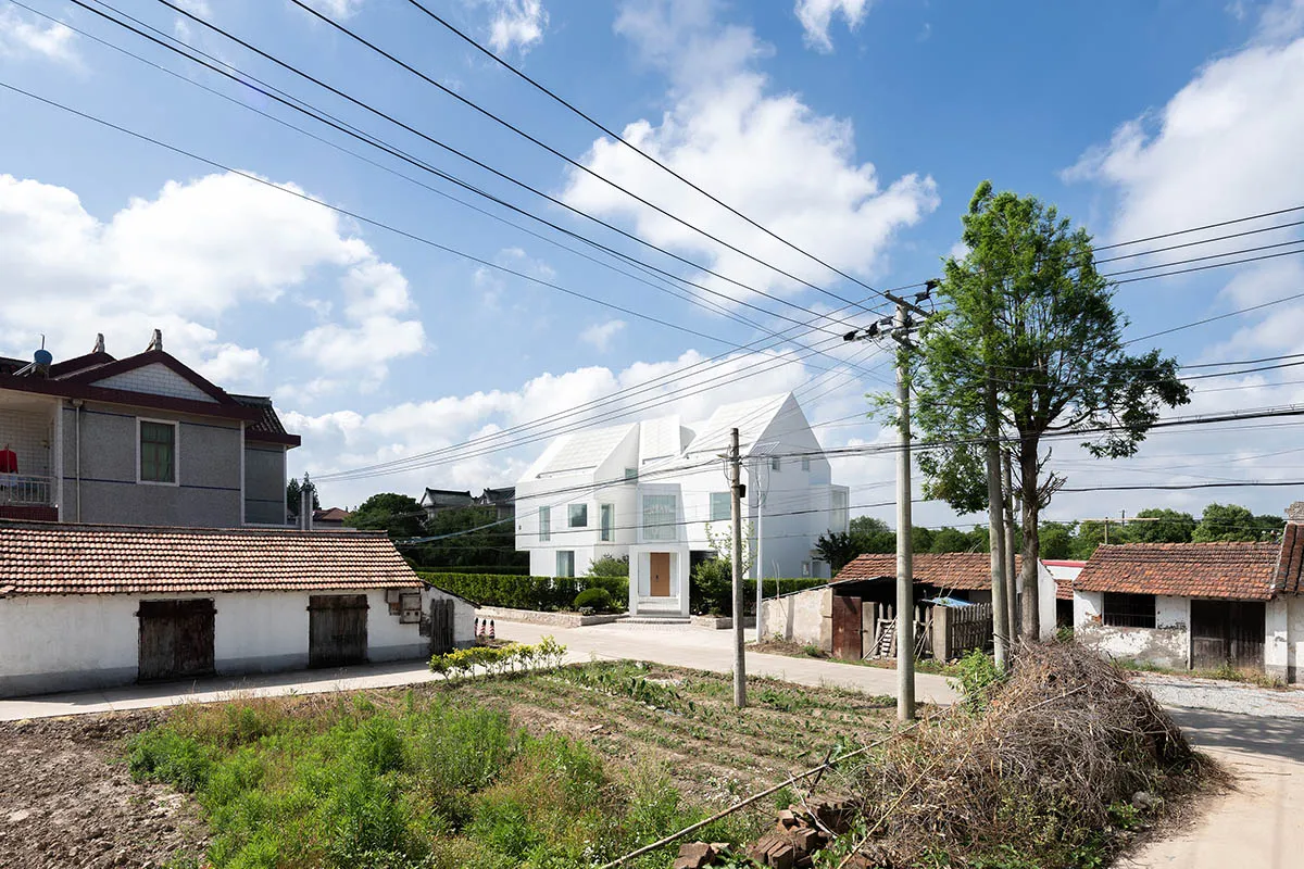 一座現代白色住宅,設有屋頂花園,背景是綠意與藍天白雲。