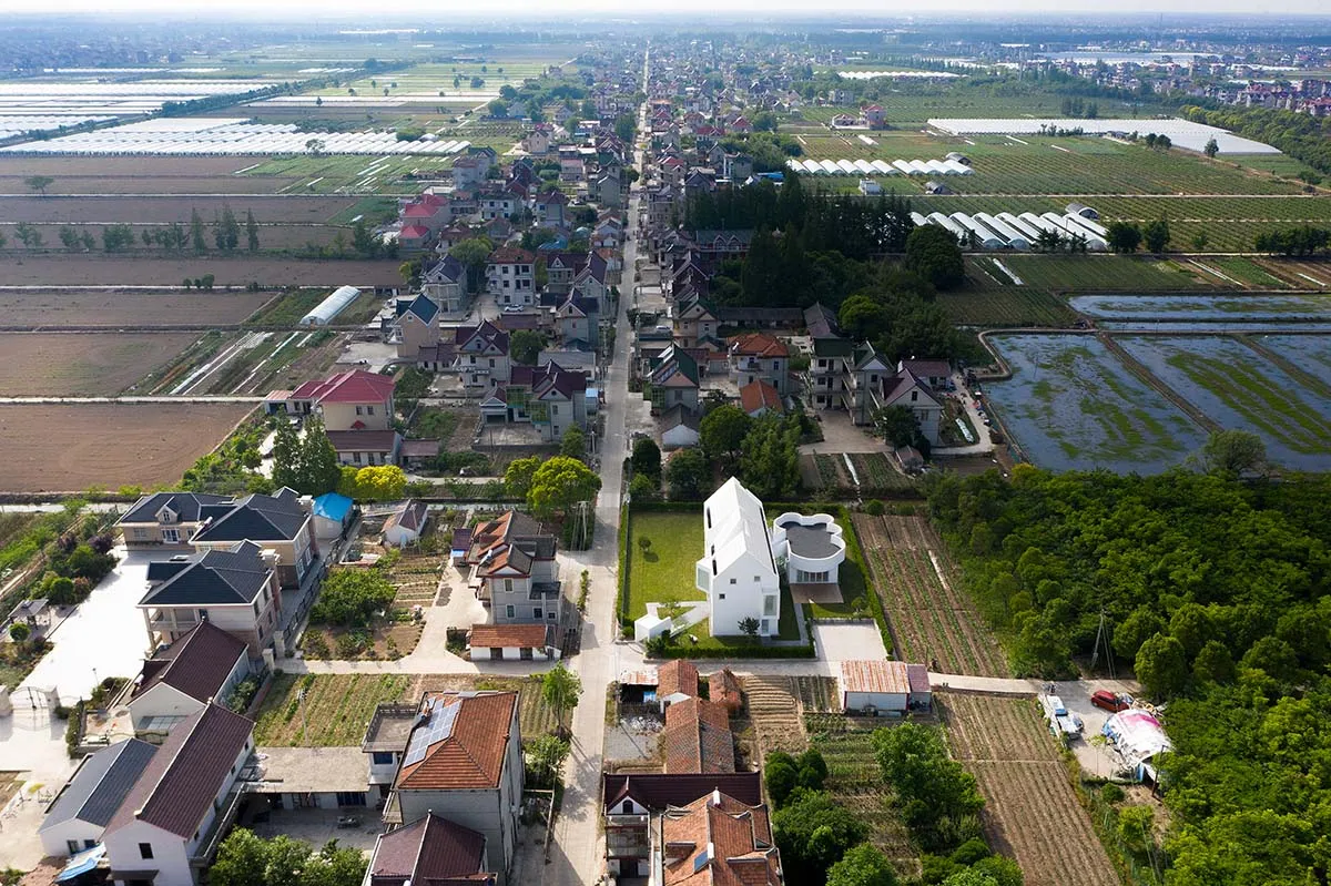 俯瞰住宅區，周圍環繞農田，中央有道路貫穿。