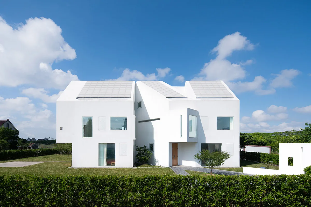 A white modern house with solar panels on the roof.