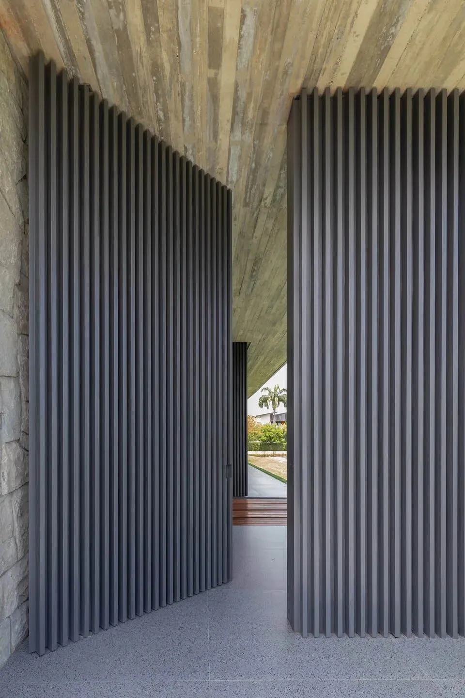 A modern architectural design featuring a wall composed of vertical concrete panels.