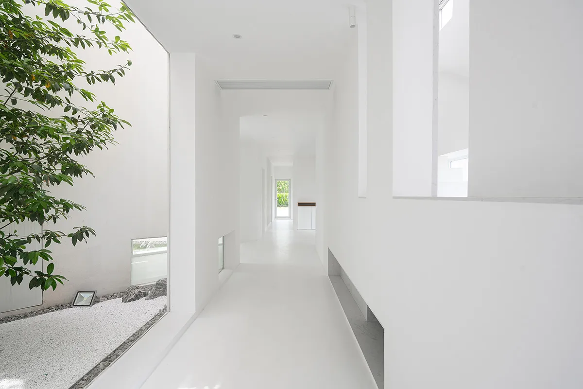 A minimalist white interior space with concrete walls and floors, featuring modern architectural elements and a clean, open d