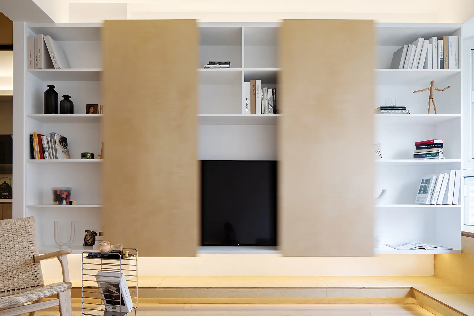 A modern living room with minimalist design features, including wood furniture, metal accents, and glass elements.