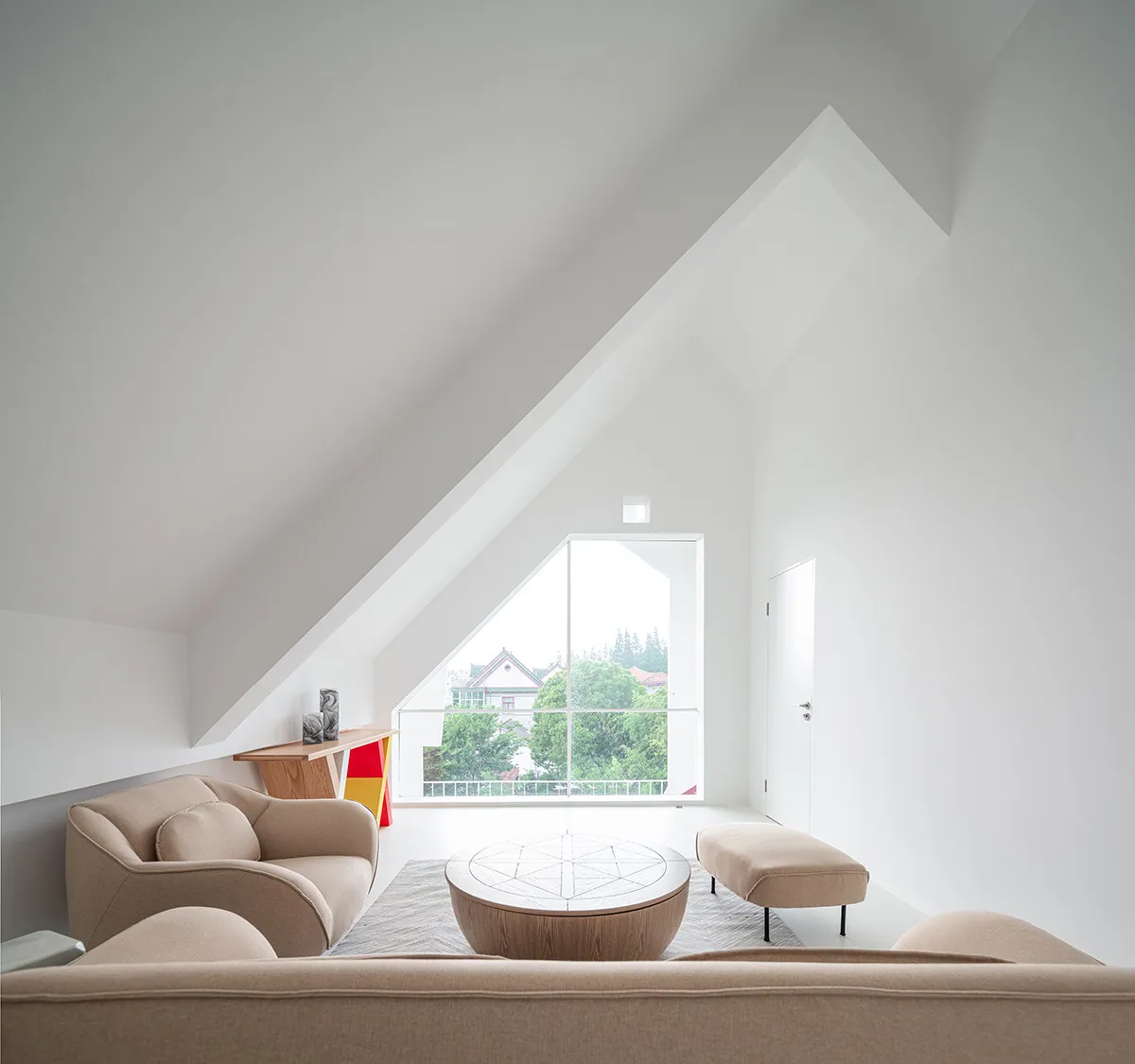 A minimalist living room with neutral-toned furniture and a large window showcasing a scenic view.