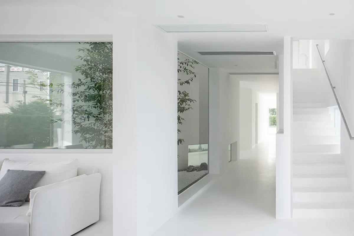 Contemporary white living room with minimalist design, white furniture, and large windows