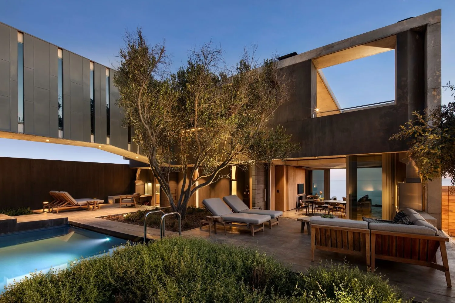 A modern residential house featuring a concrete and glass exterior with a pool and terrace.
