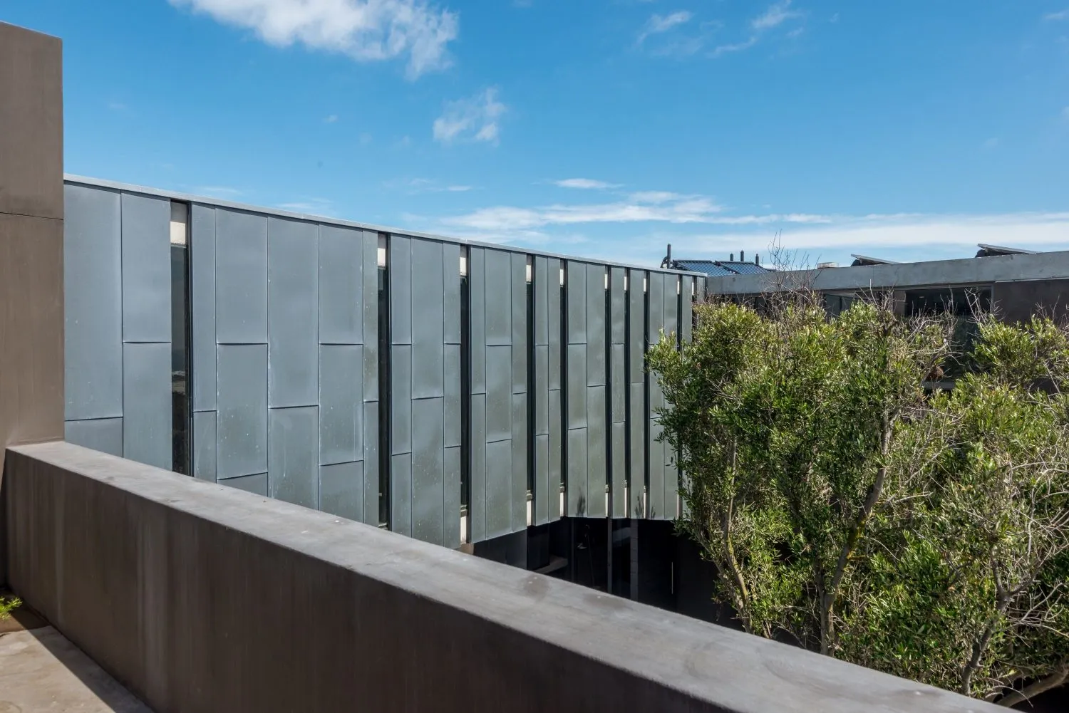 Minimalist building with metallic wall panels against a blue sky.