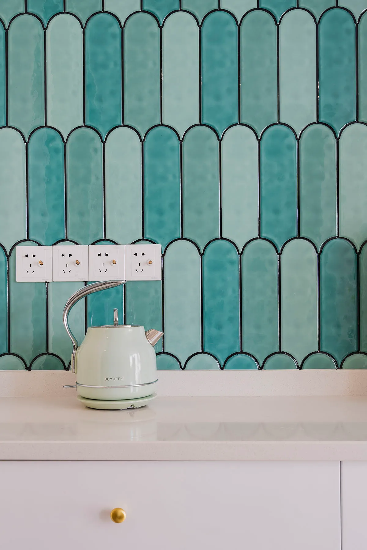 A modern kitchen with a white countertop and blue ceramic tiles on the wall.